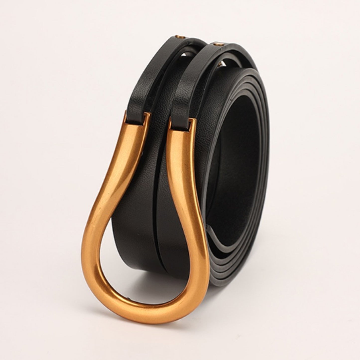 Black leather belt with a gold buckle on a light gray background
