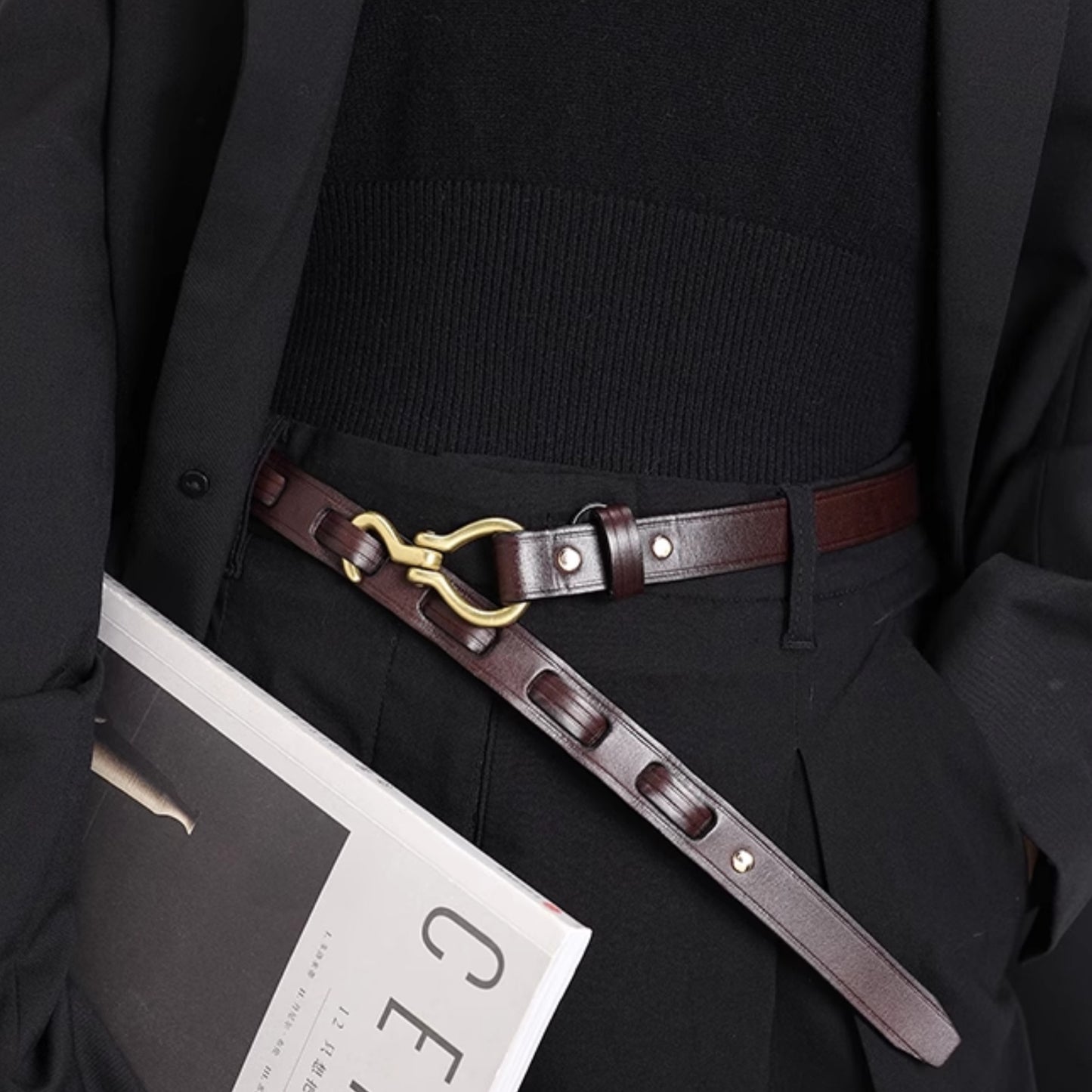 Person wearing a dark suit with a brown leather belt featuring a gold buckle.