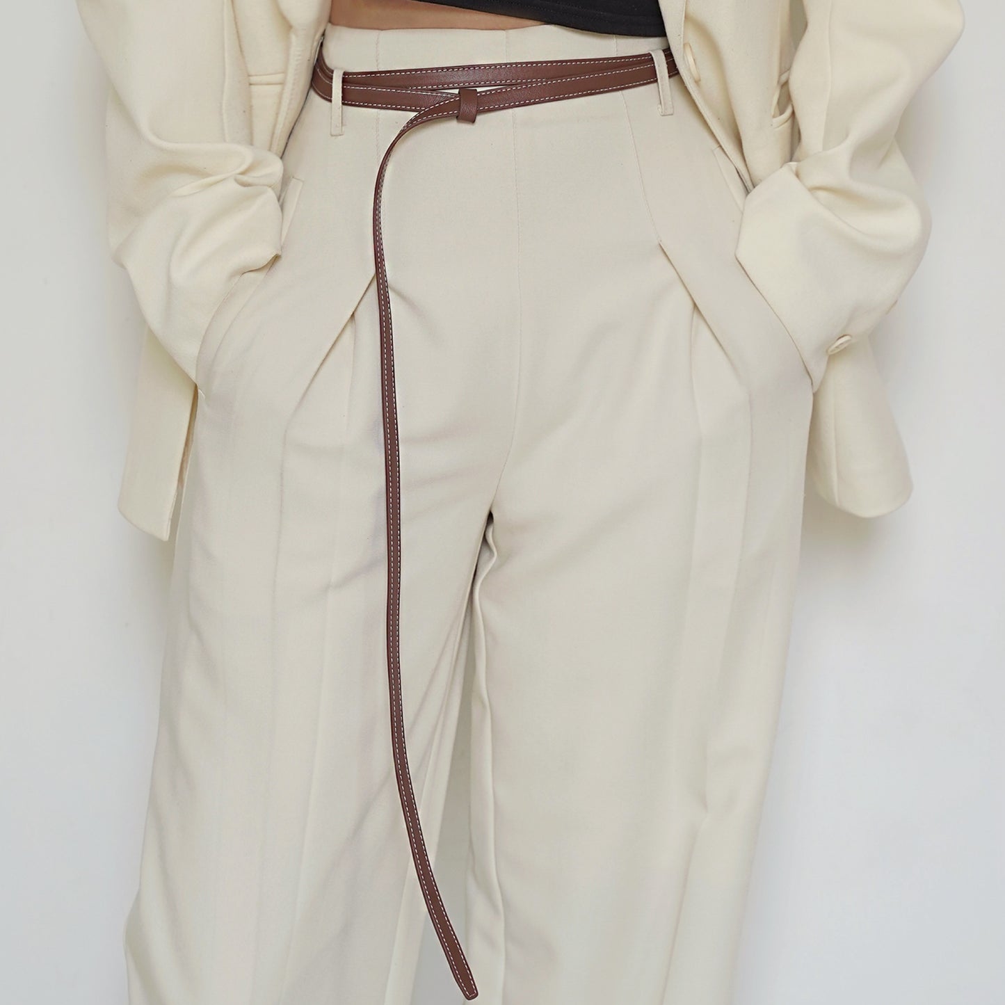 Beige pants with a brown belt on a white background