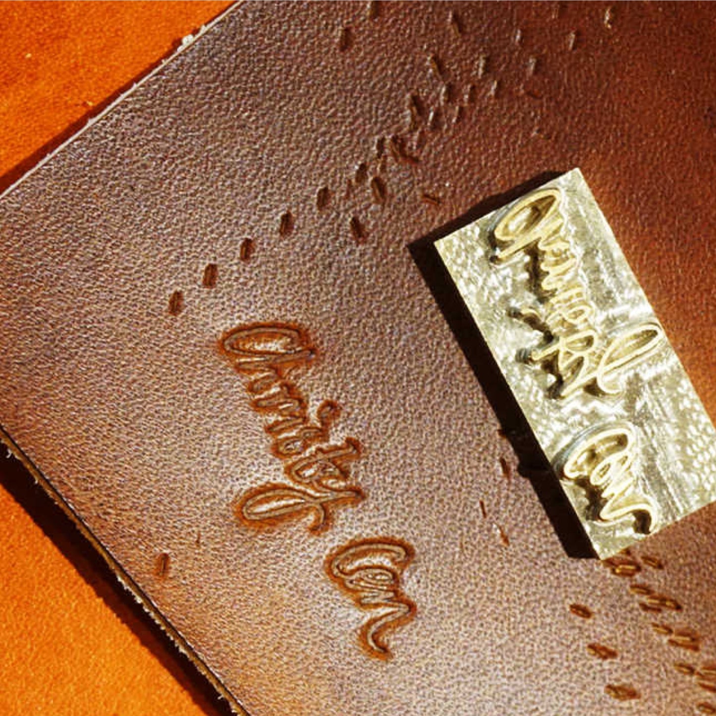Brown leather product with 'Oxbow' branding and a gold stamp on an orange background