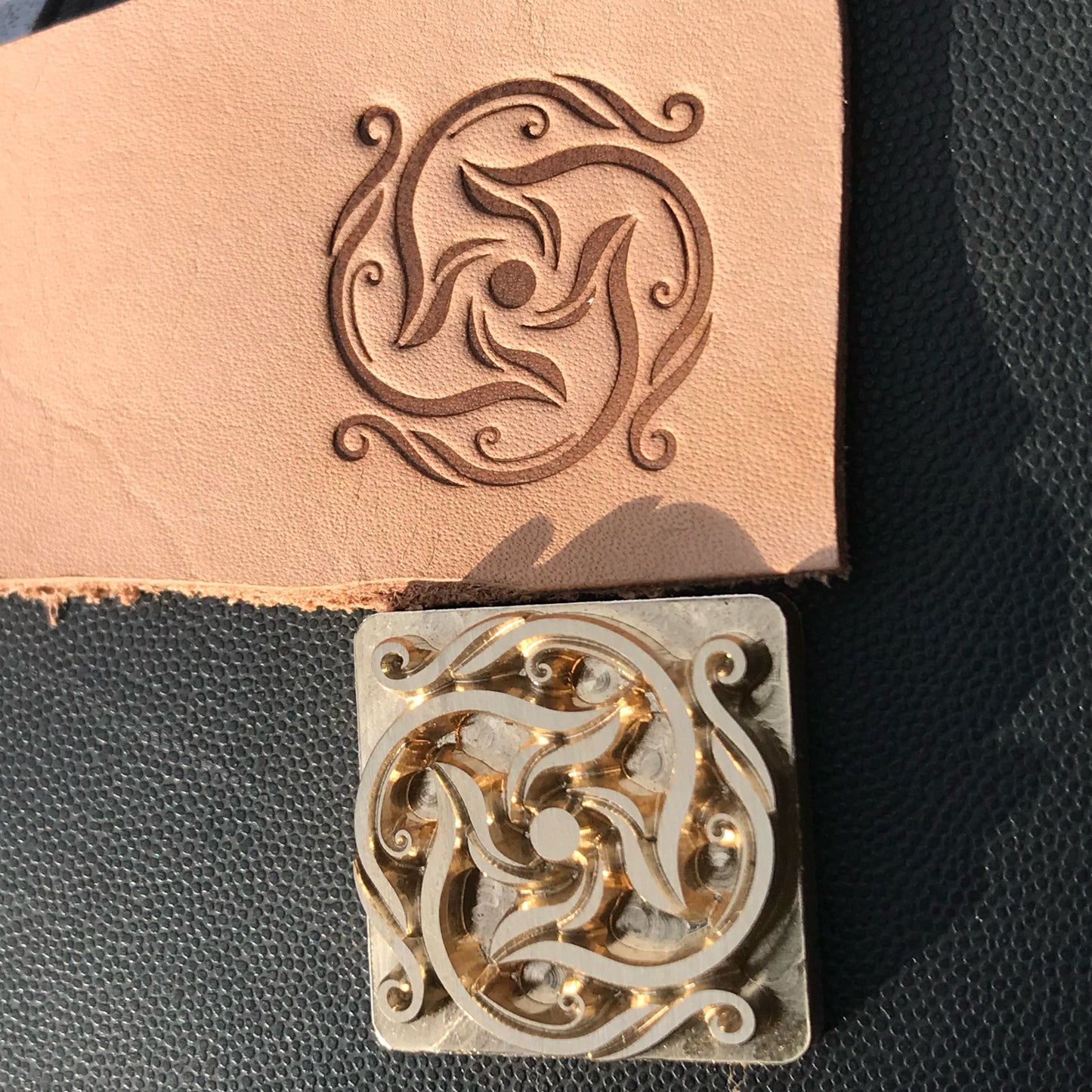 Decorative leather stamp with intricate design on a black leather background