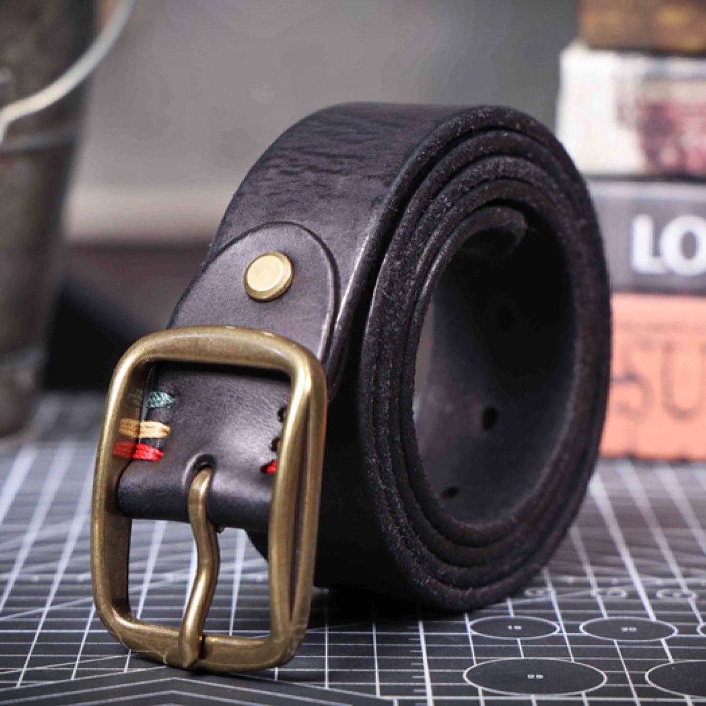 coffee leather belt with a gold buckle on a grid surface