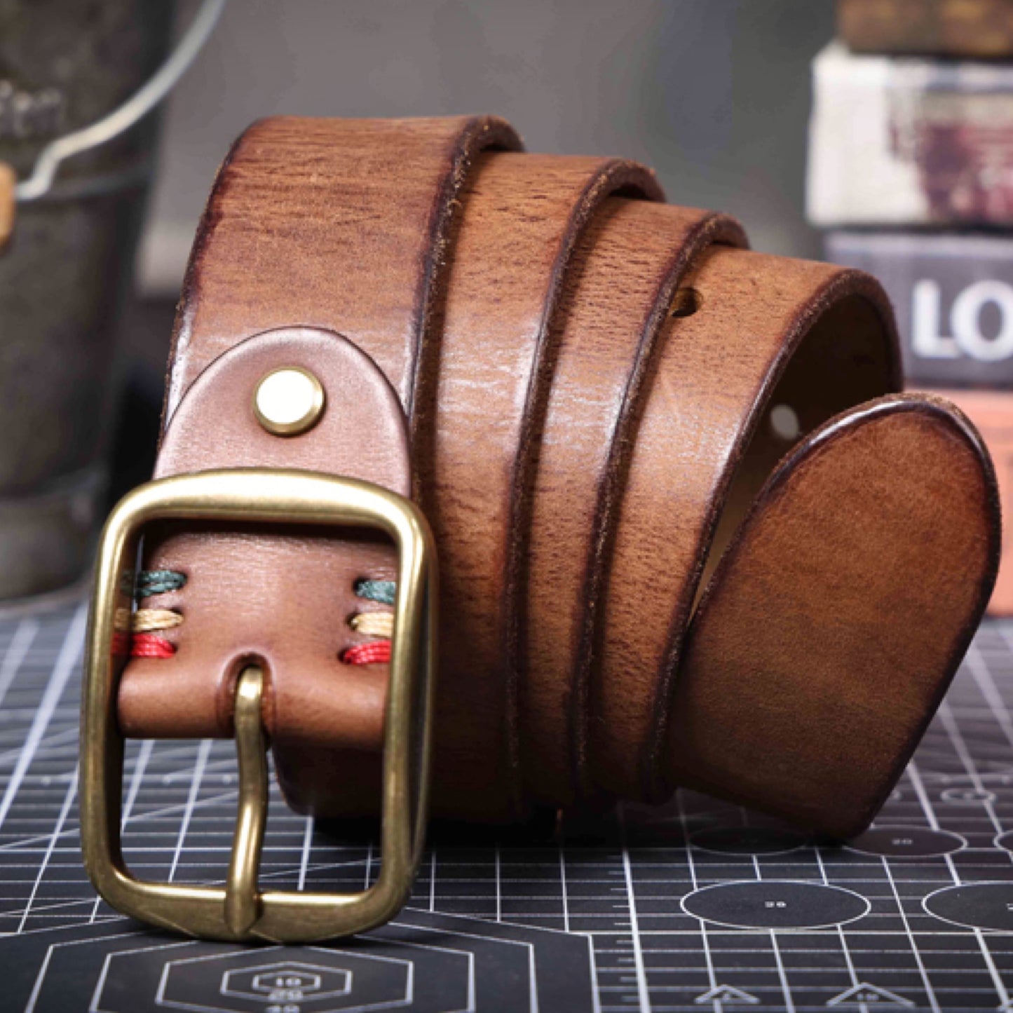 Brown leather belt with a gold buckle on a grid background