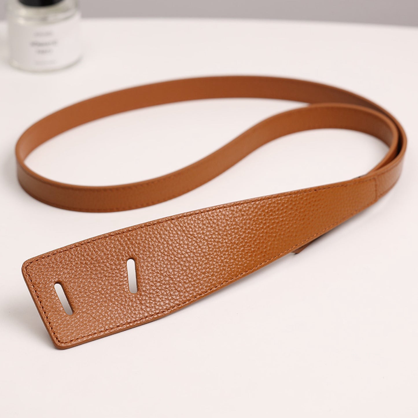 Brown leather belt on a white surface