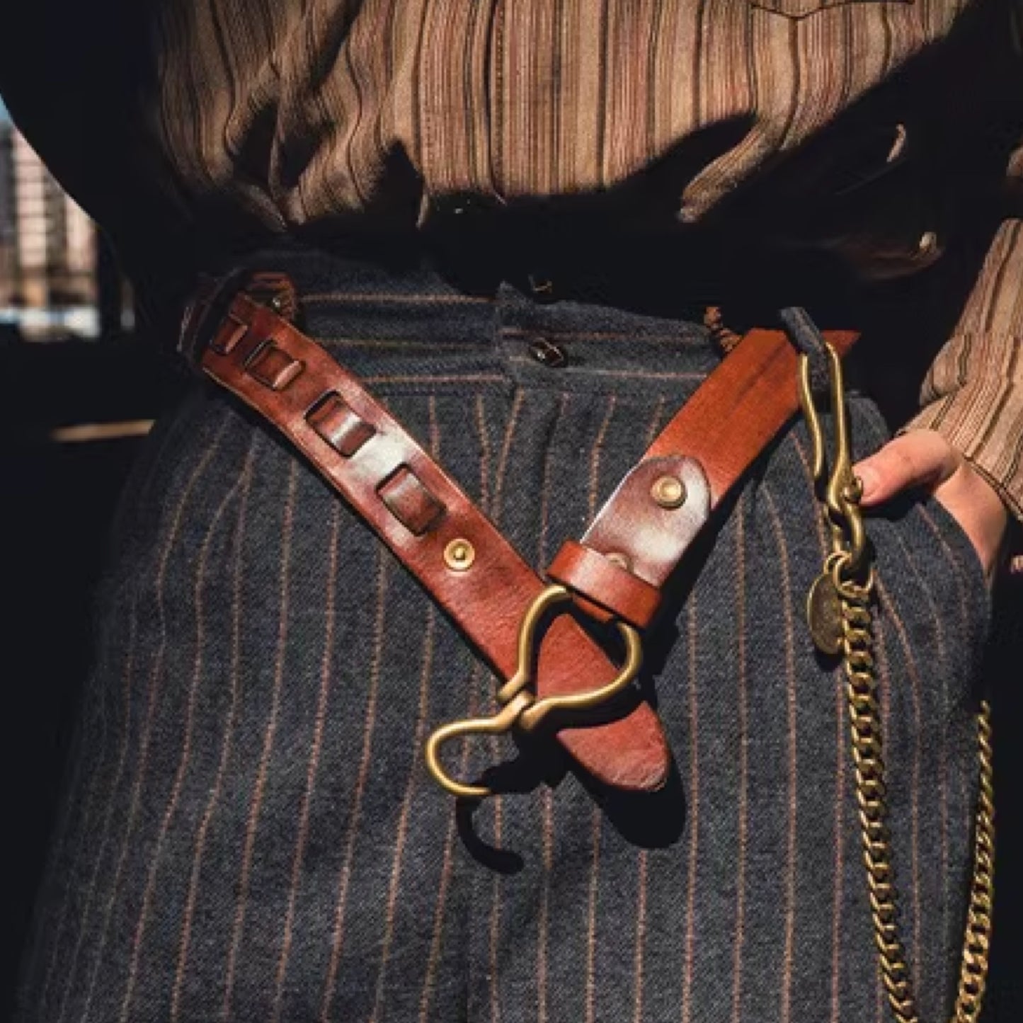 Close-up of a person wearing a leather strap with gold hardware on a dark background