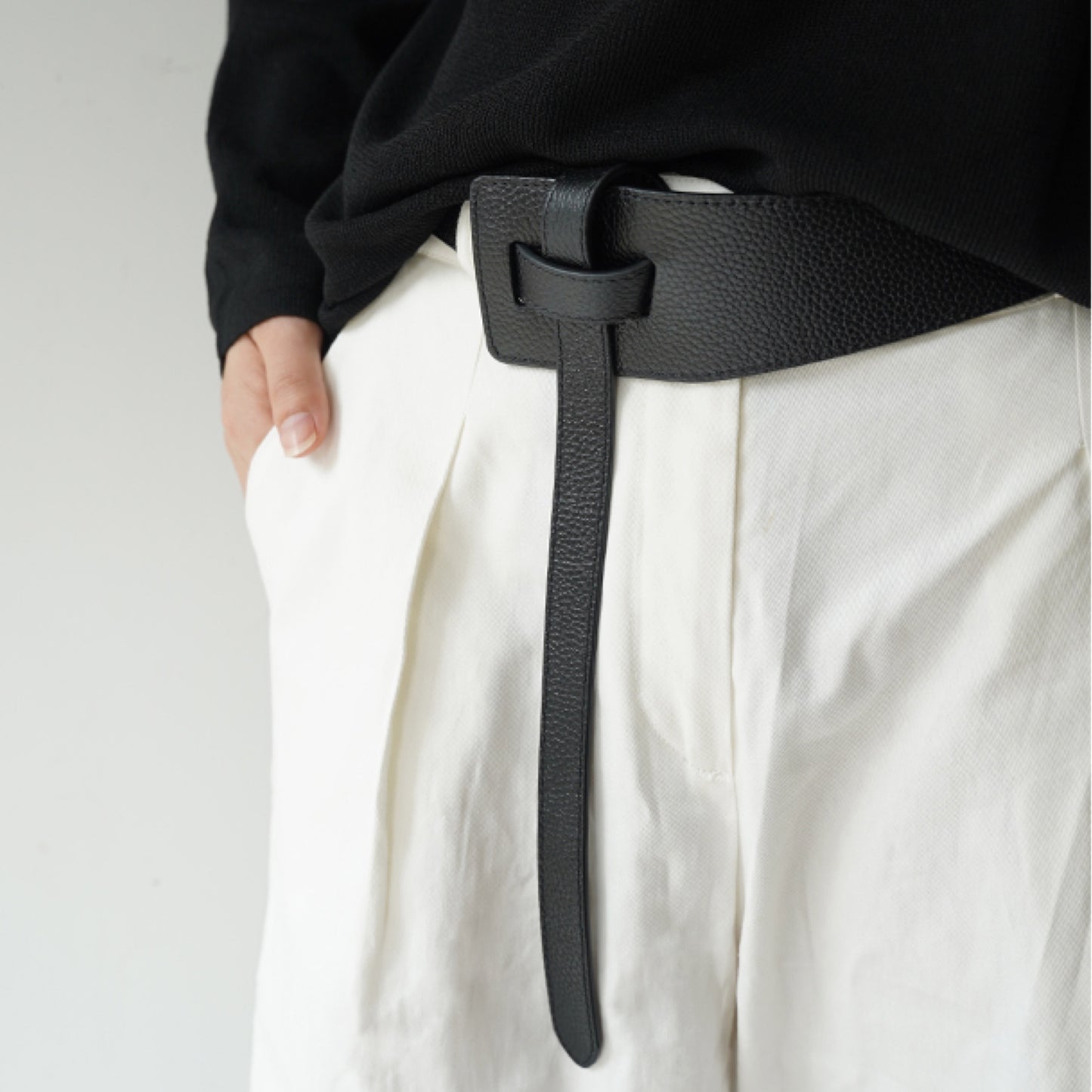 Person wearing a black belt with a plain background