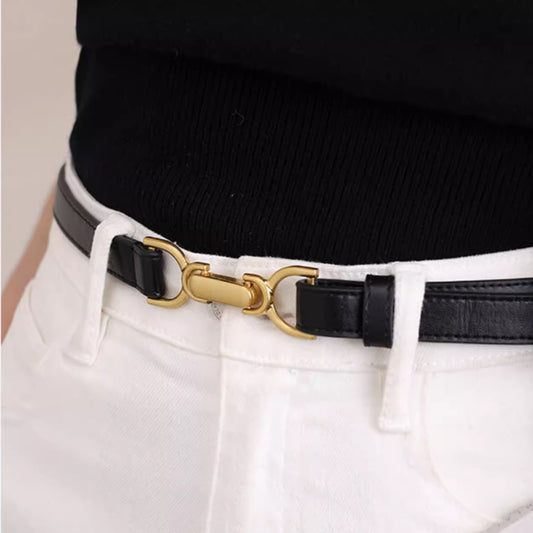 Black belt with a gold buckle worn by a person in white pants.