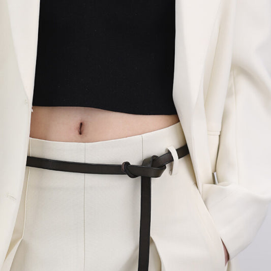 Person wearing a white outfit with a black belt and black top.