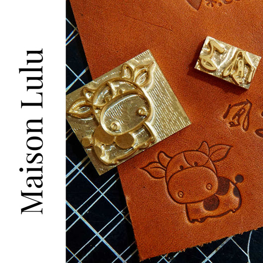 Gold stamp with a design on leather, branded 'Maison Lulu'.