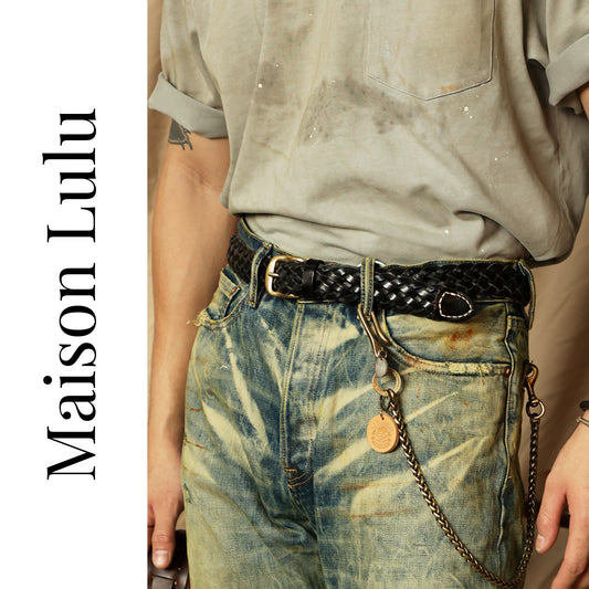 Person wearing a belt with a chain detail, featuring the brand 'Maison Lulu'.