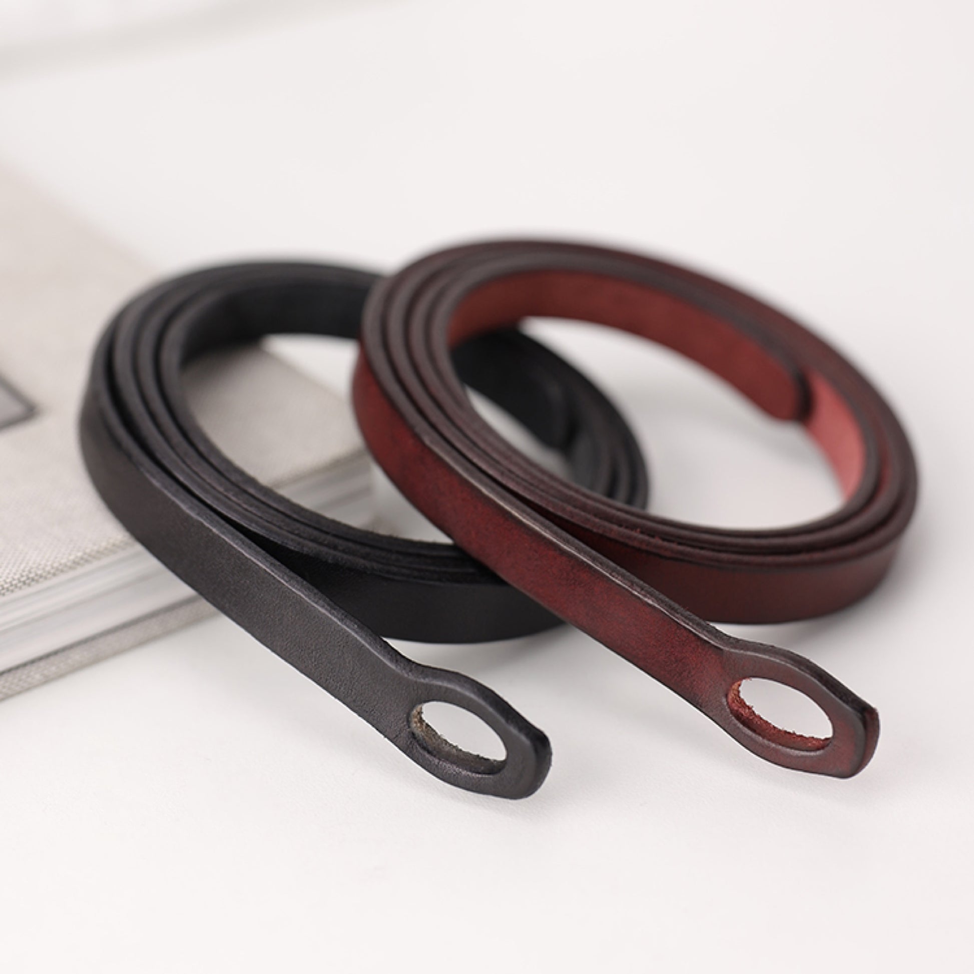 Black and brown leather belts on a white surface