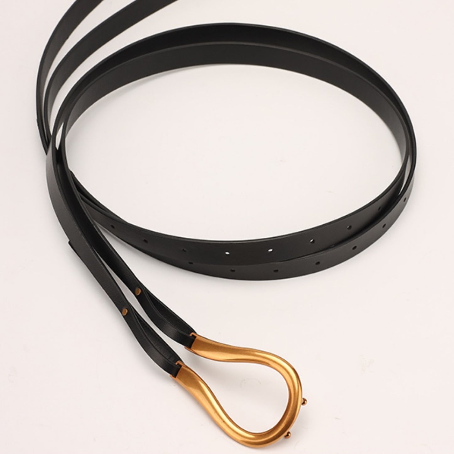 Black belt with a gold buckle on a light gray background