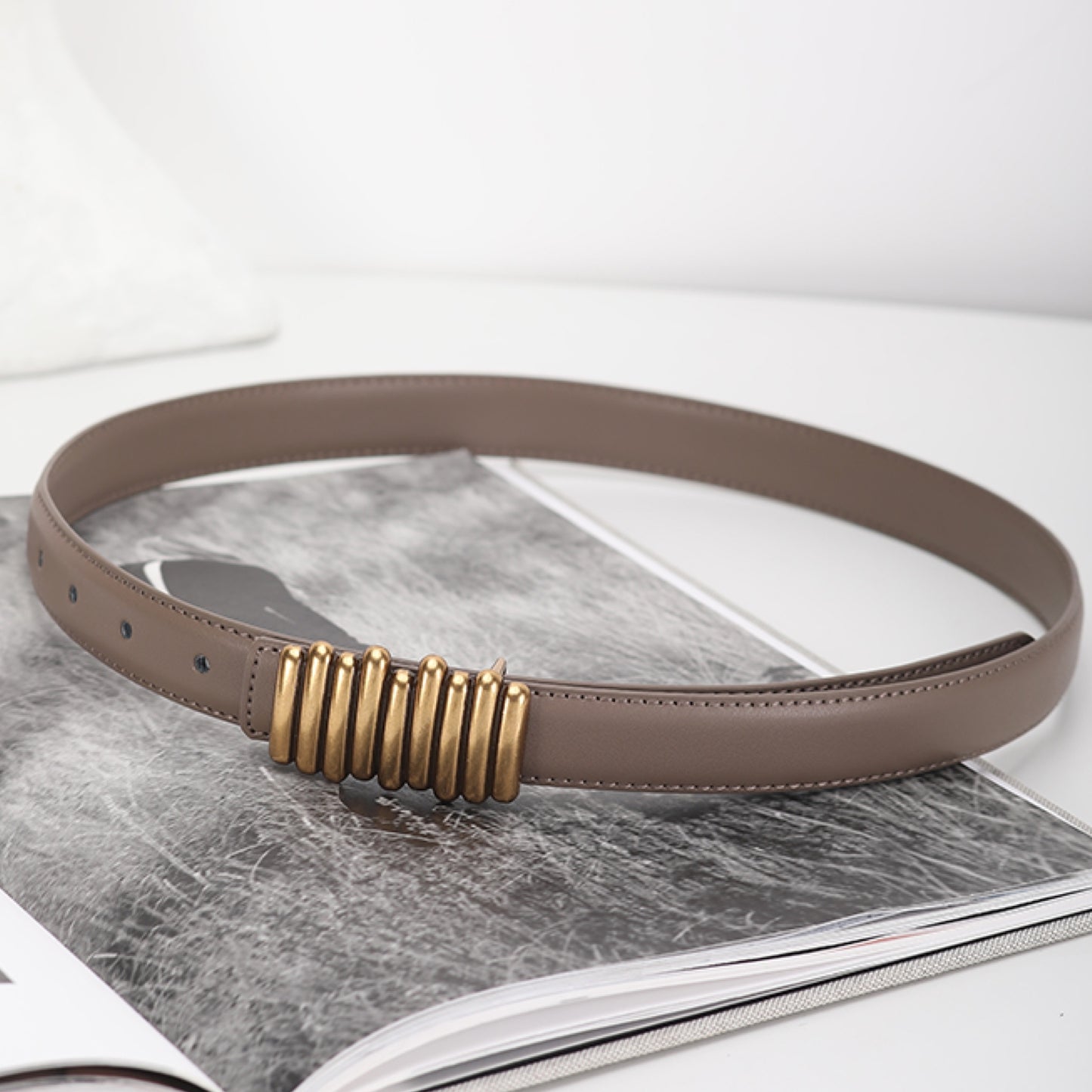 Brown belt with a gold buckle on a marble surface