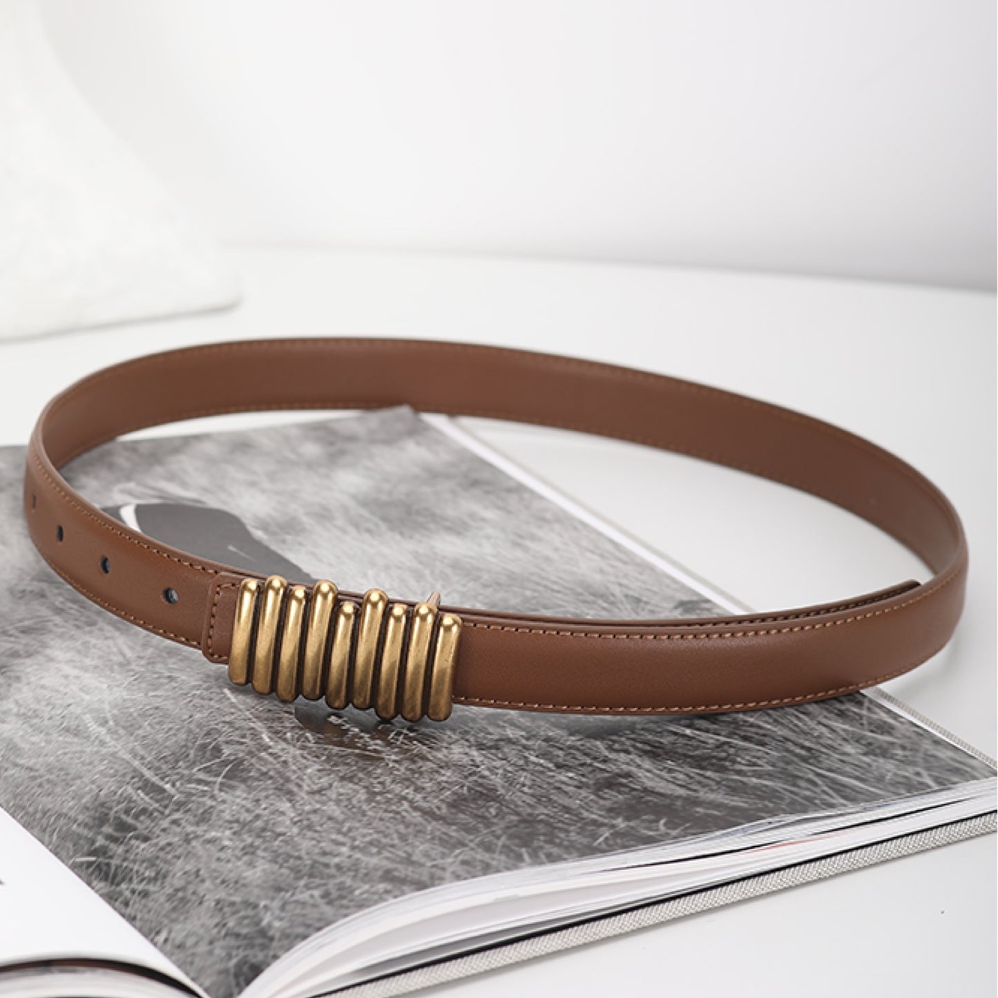 Brown belt with gold buckle on a magazine