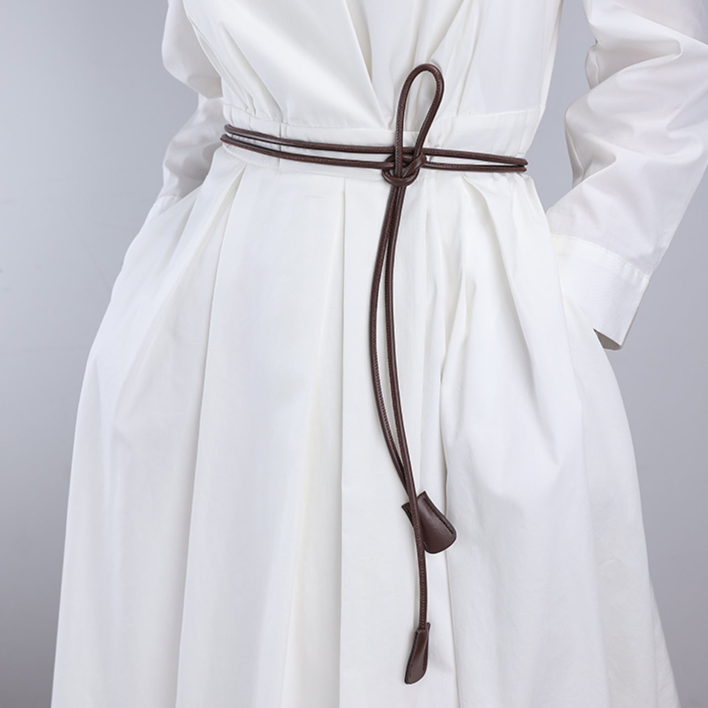 White dress with a brown belt on a gray background
