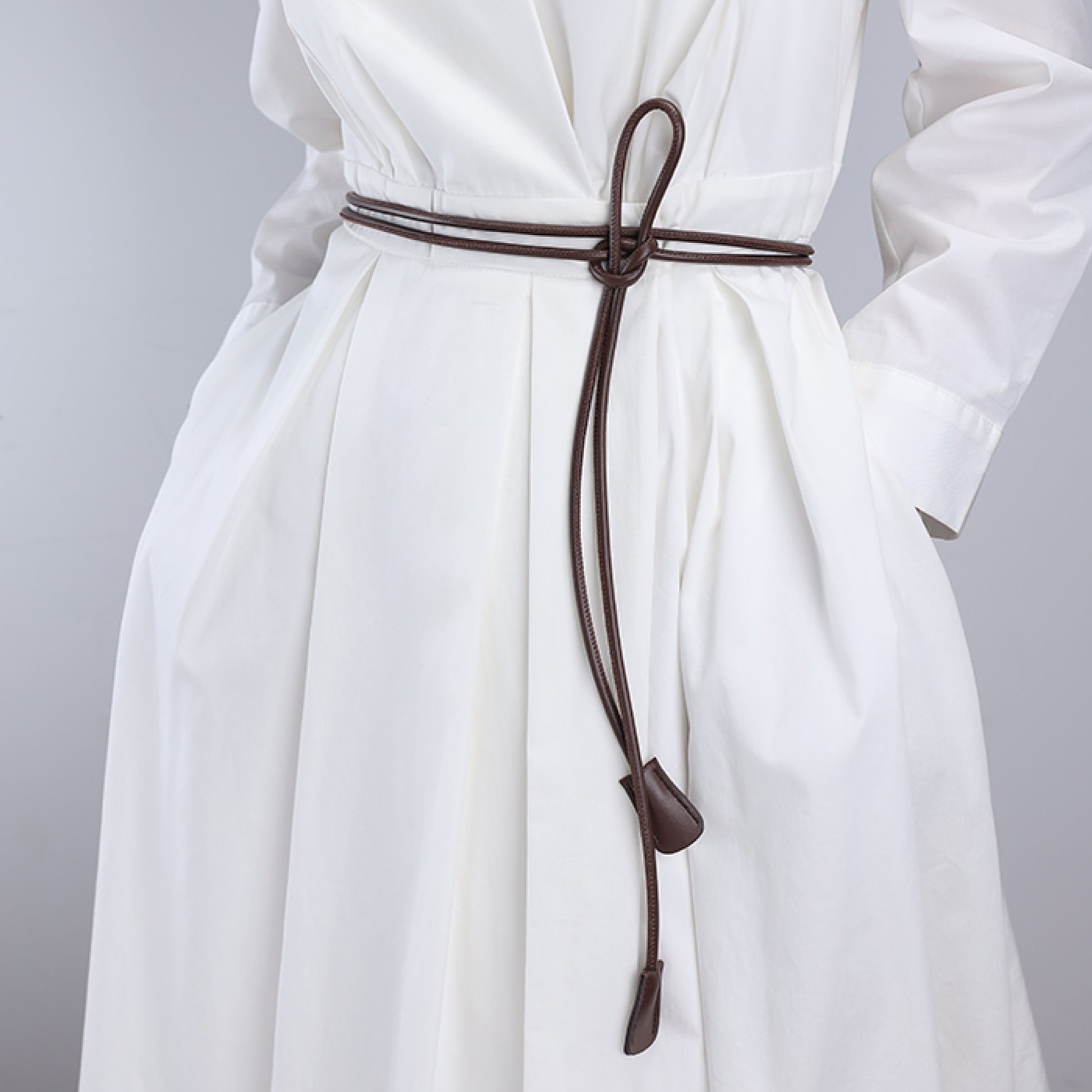 White dress with a brown belt on a gray background
