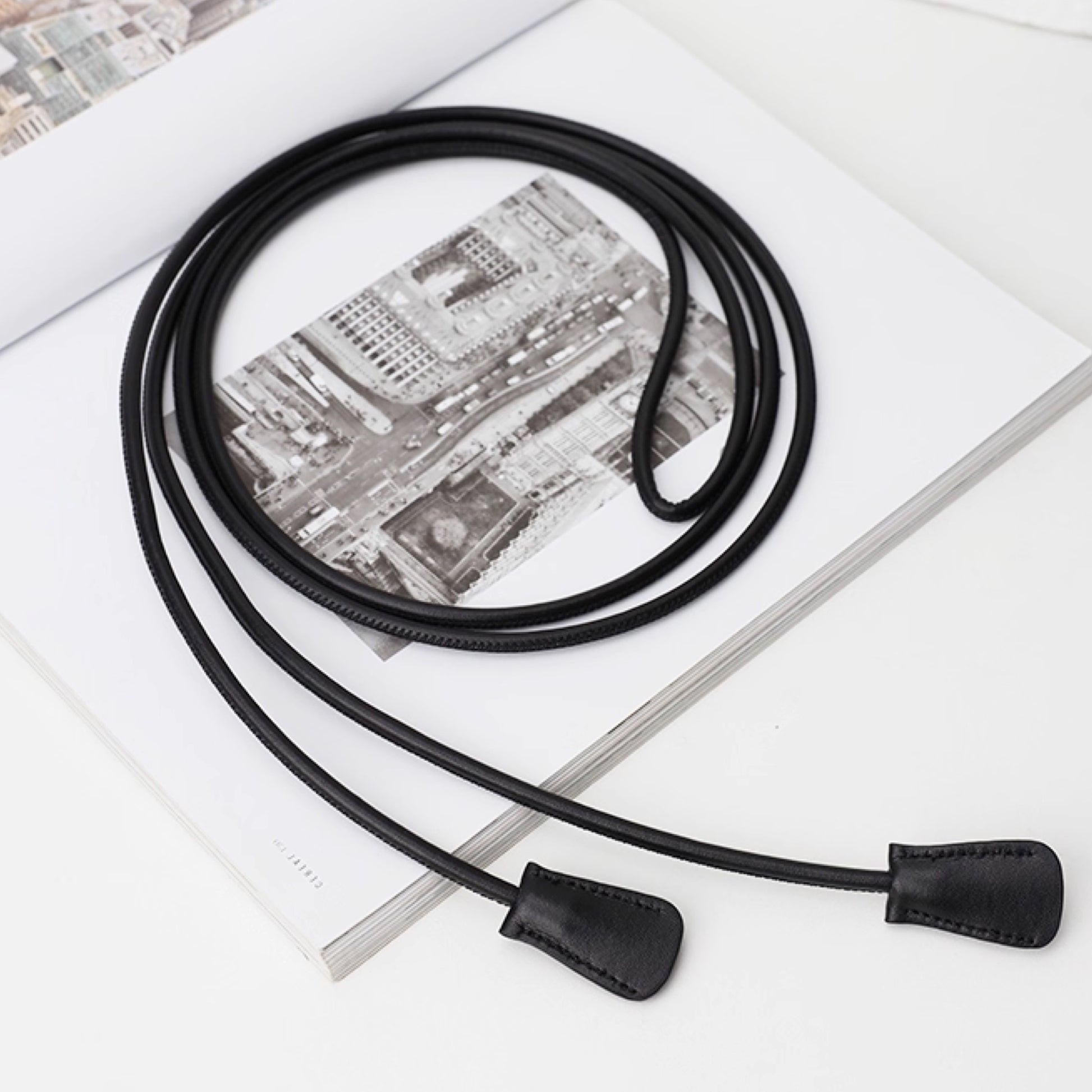Black leather lanyard with metal clip on a newspaper background
