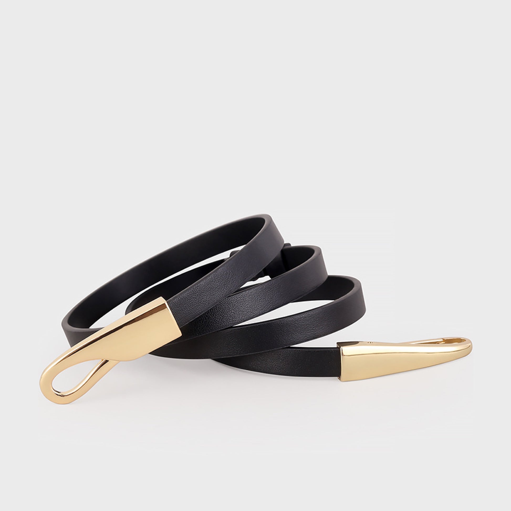 Black leather belt with gold hardware on a light gray background