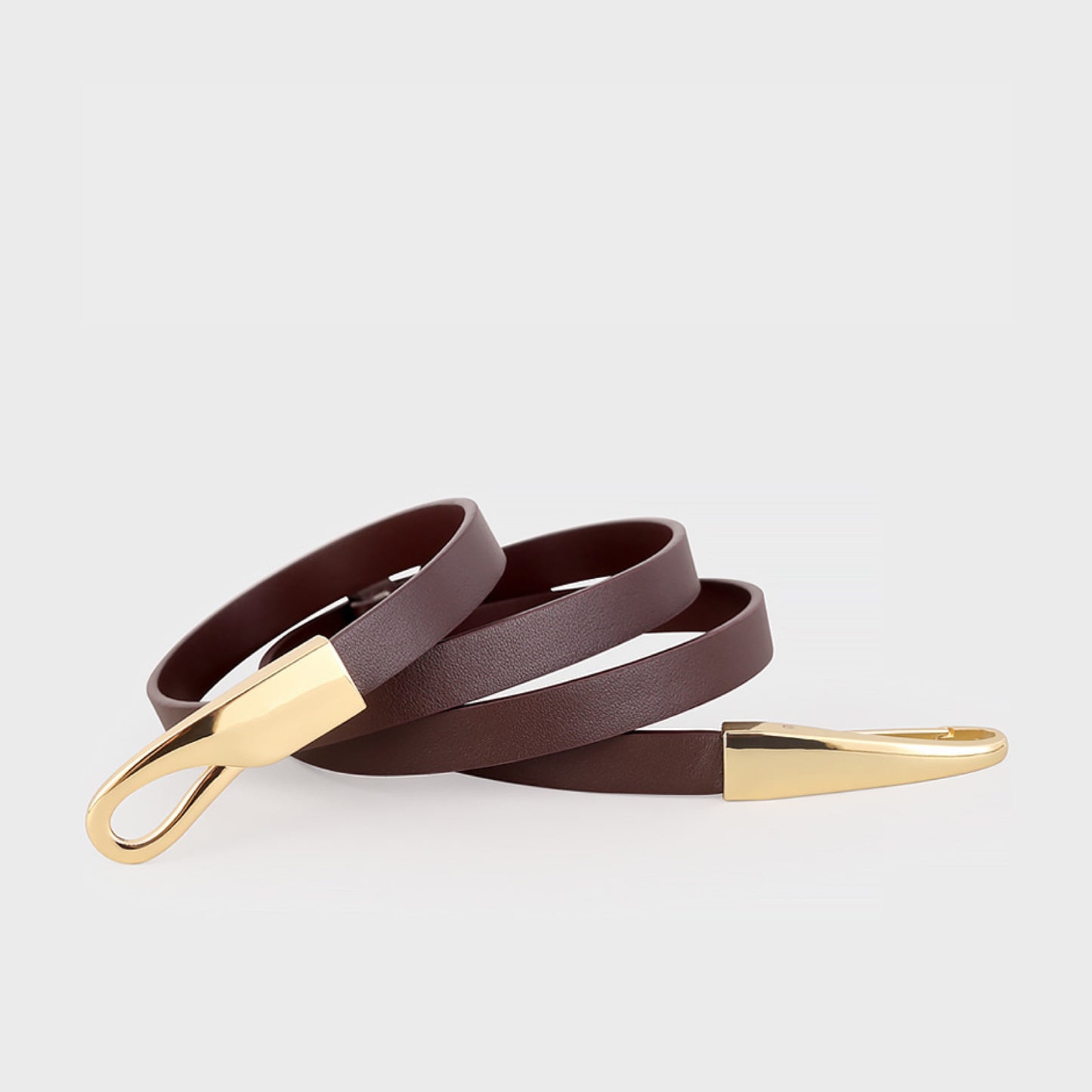 Brown leather belt with gold buckle on a light gray background
