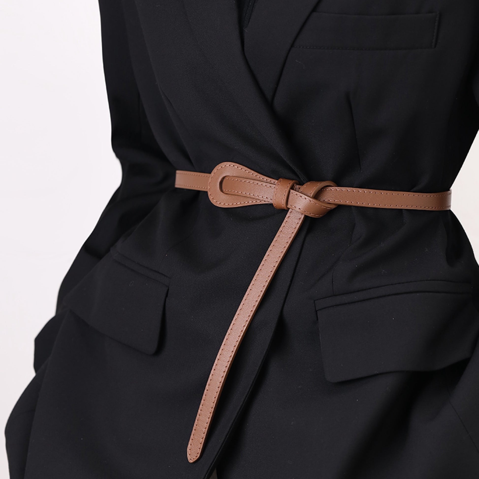 Black outfit with a brown belt on a light gray background