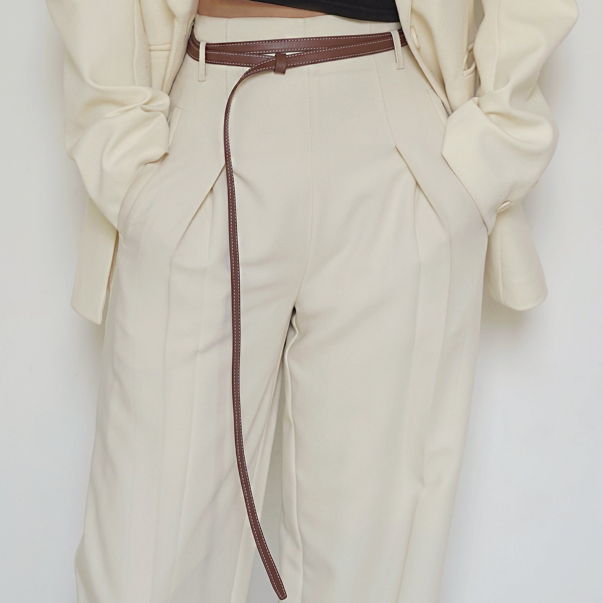 Beige pants with a brown belt on a white background