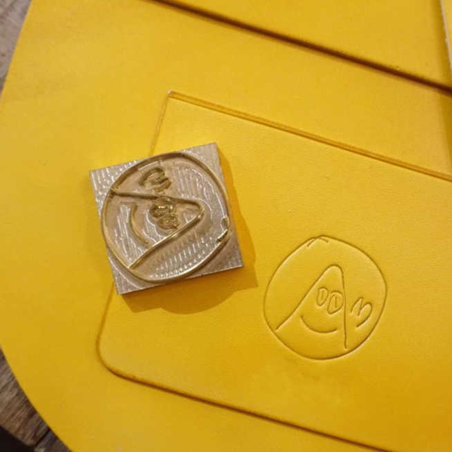 Metallic badge on a yellow surface with embossed design