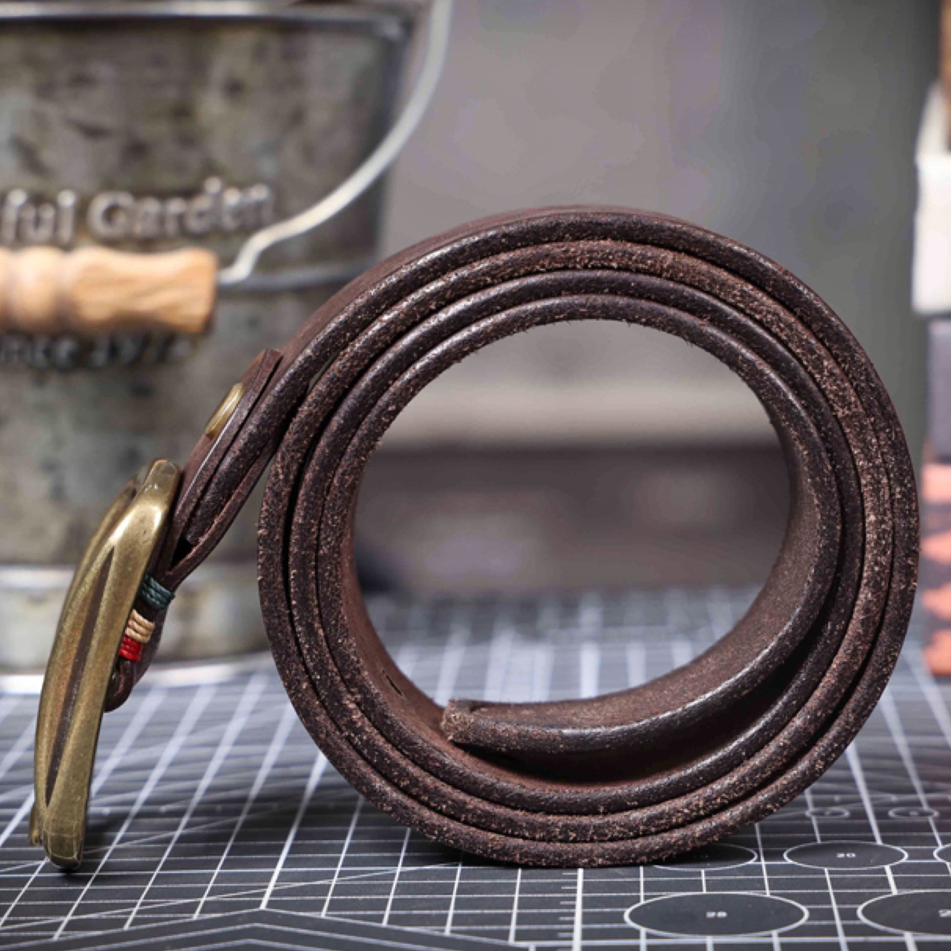 Brown leather belt with brass buckle on a cutting mat