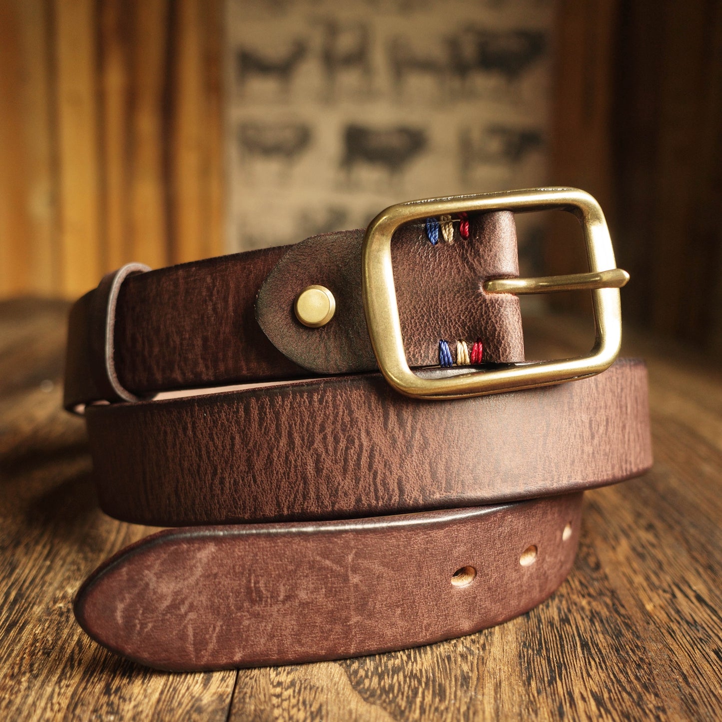 Brown leather belt with a gold buckle on a wooden surface