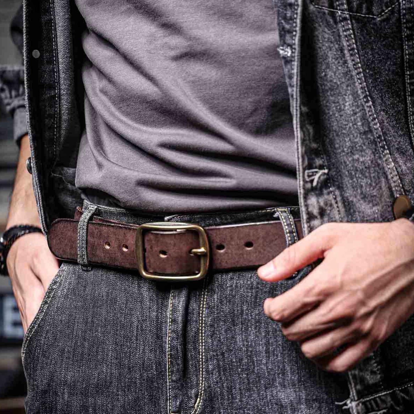 Person wearing a brown belt with a gold buckle, gray shirt, and denim jacket.