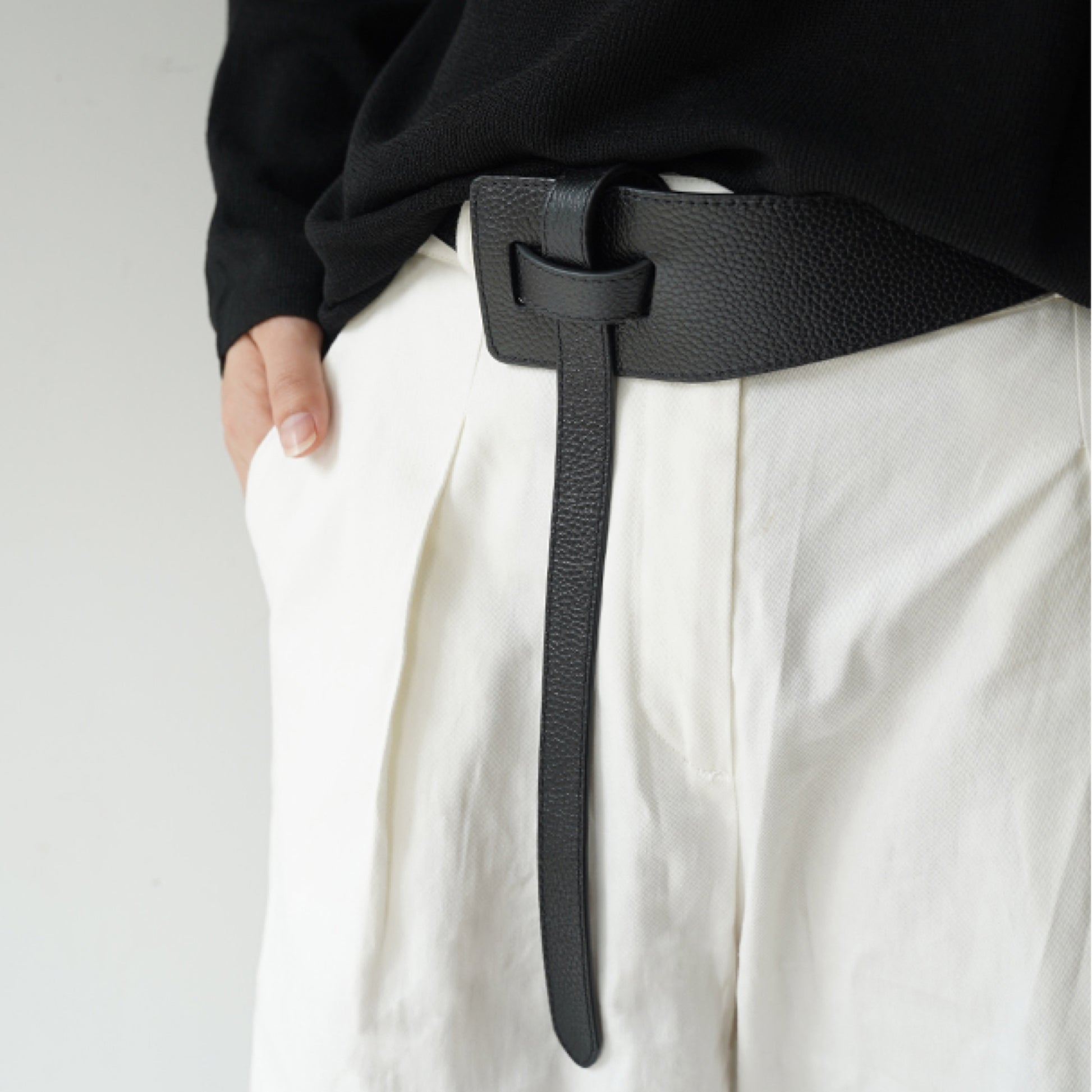 Person wearing a black belt with a plain background