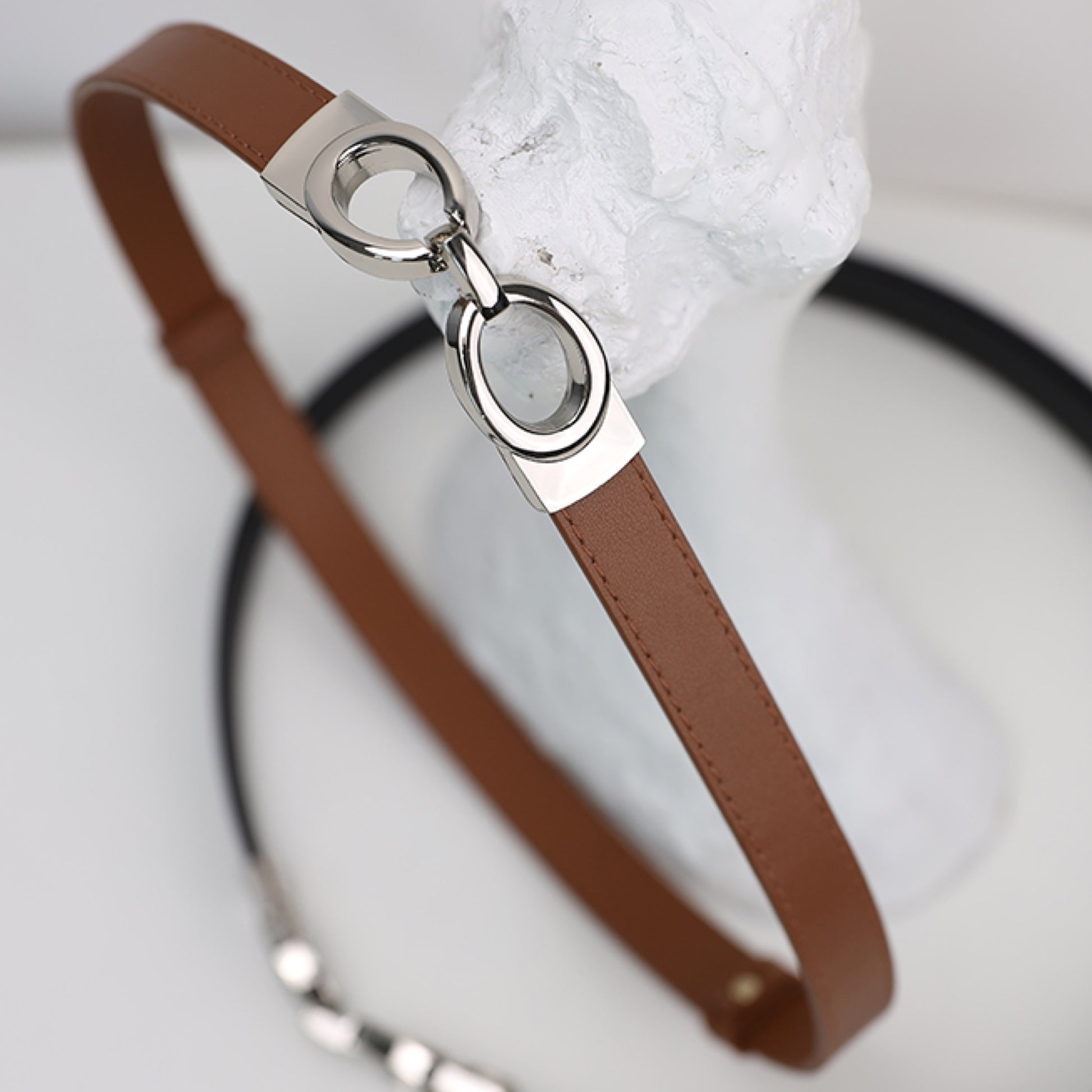 Brown leather strap with silver clasp on a light gray background