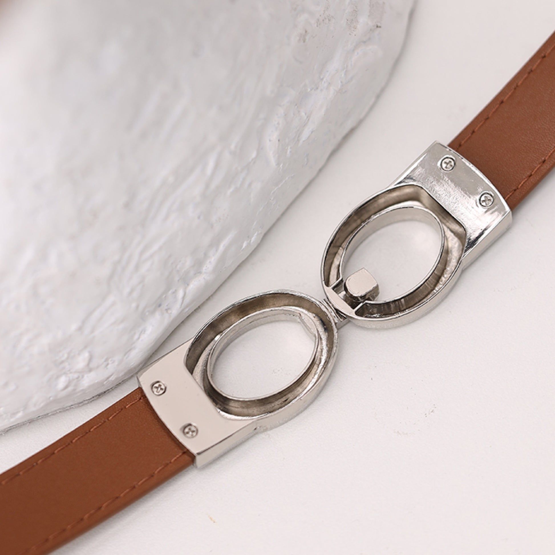 Brown belt with silver buckle on a light background