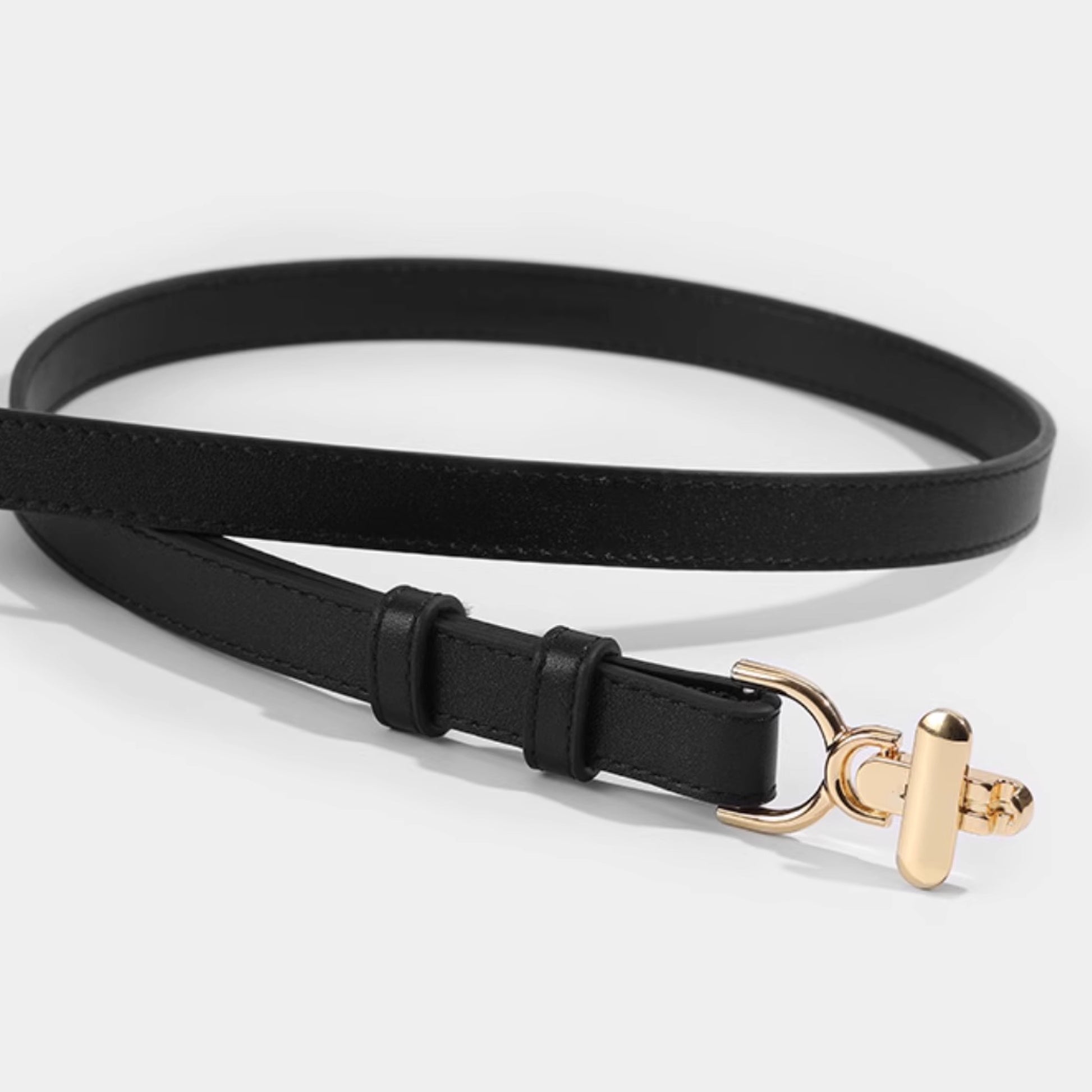 Black belt with a gold buckle on a light gray background