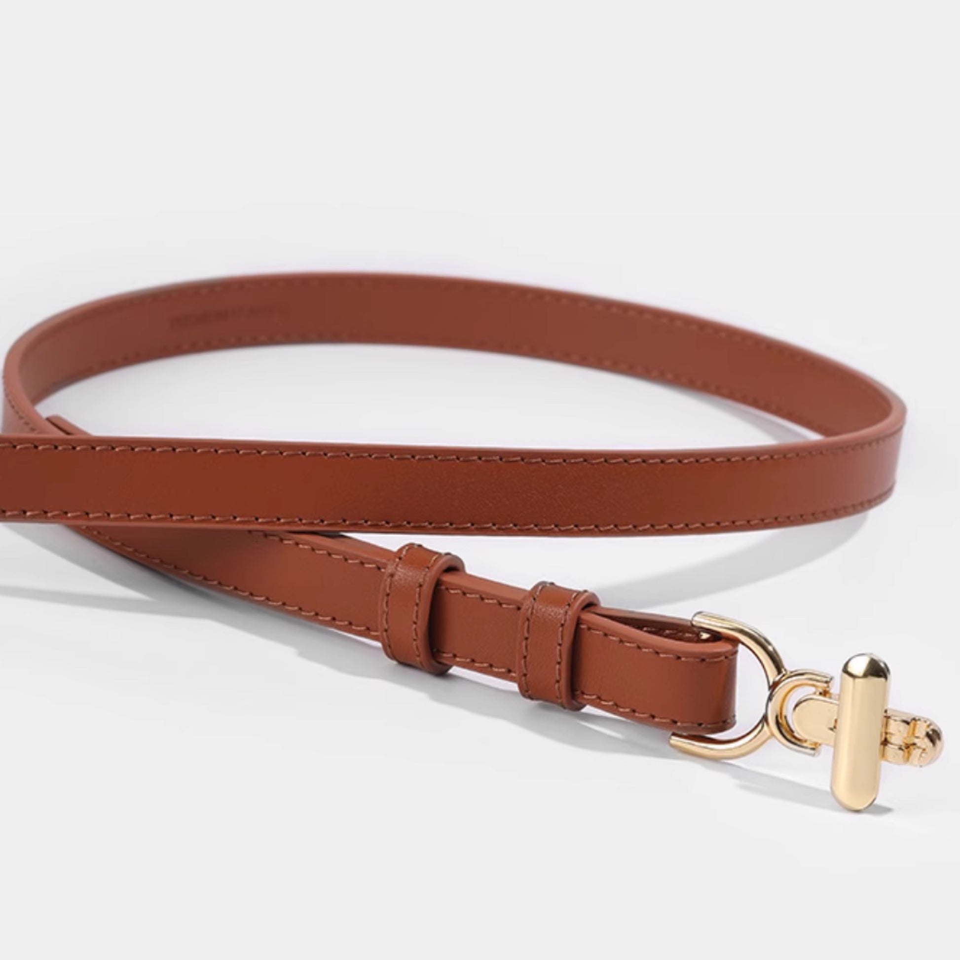 Brown leather belt with a gold buckle on a light gray background